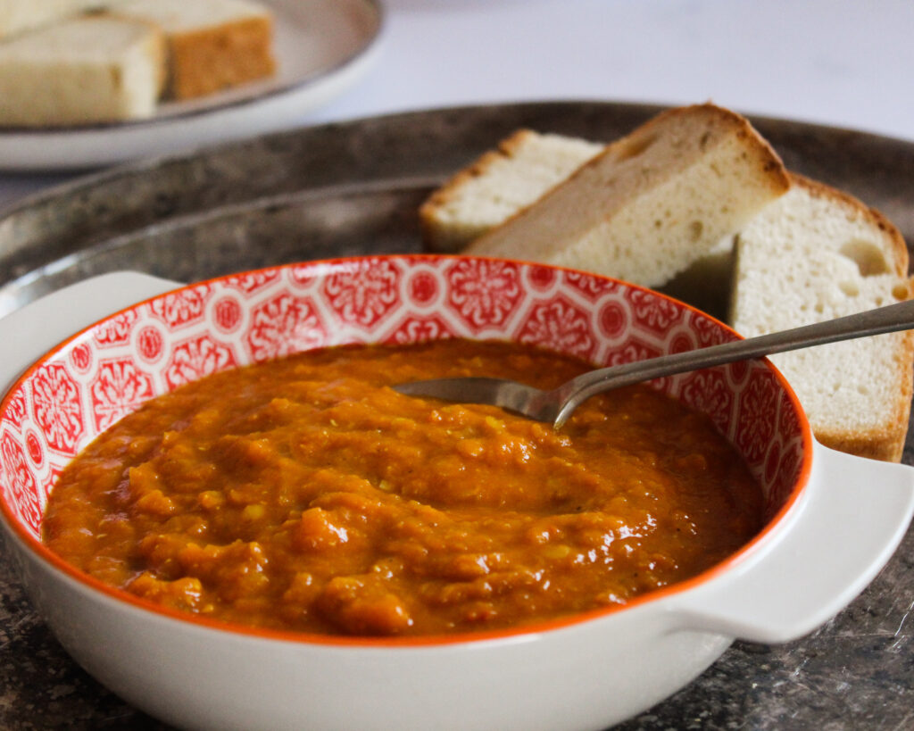 Red lentil soup in a bowl with bread on the side